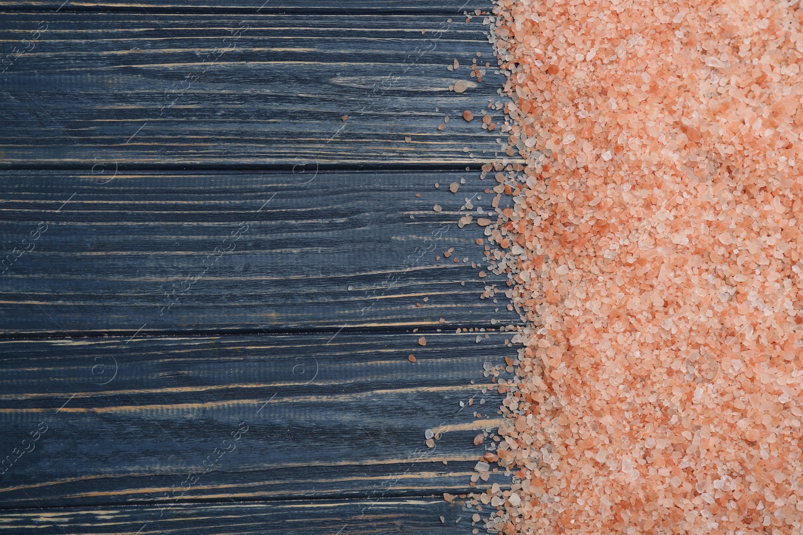 Photo of Pink himalayan salt on blue wooden table, flat lay. Space for text