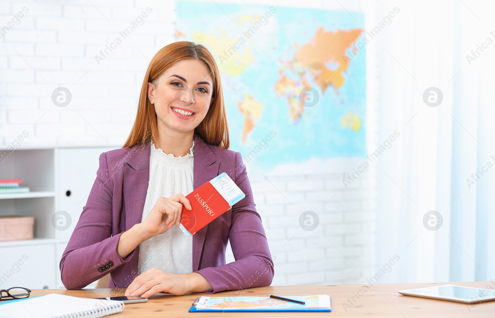 Photo of Beautiful consultant holding passport with ticket in travel agency. Space for text