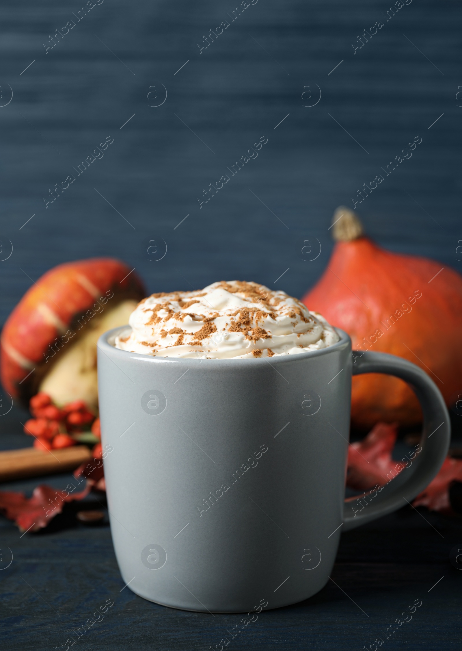 Photo of Cup with tasty pumpkin spice latte on blue wooden table