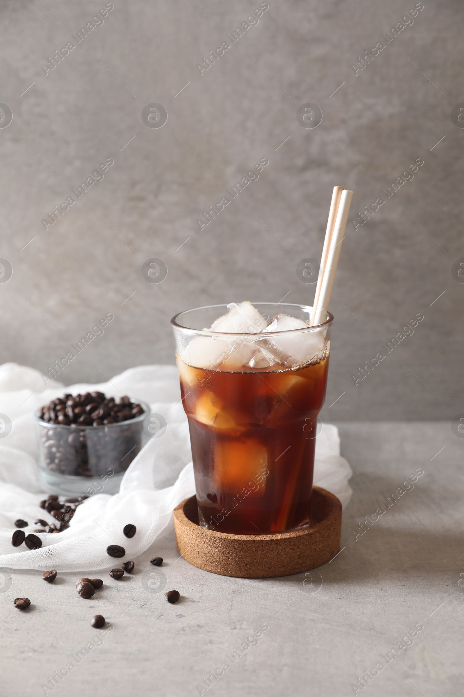 Photo of Refreshing iced coffee in glass and beans on gray table