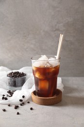 Photo of Refreshing iced coffee in glass and beans on gray table