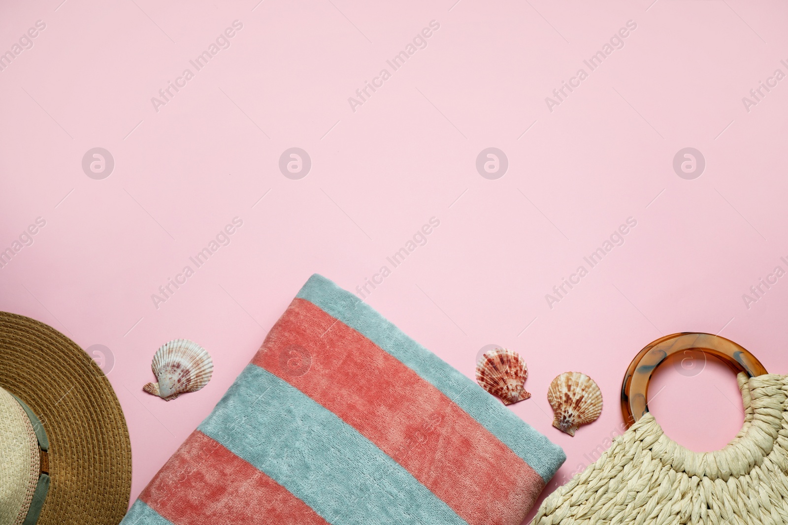 Photo of Beach towel, straw hat and bag on pink background, flat lay. Space for text