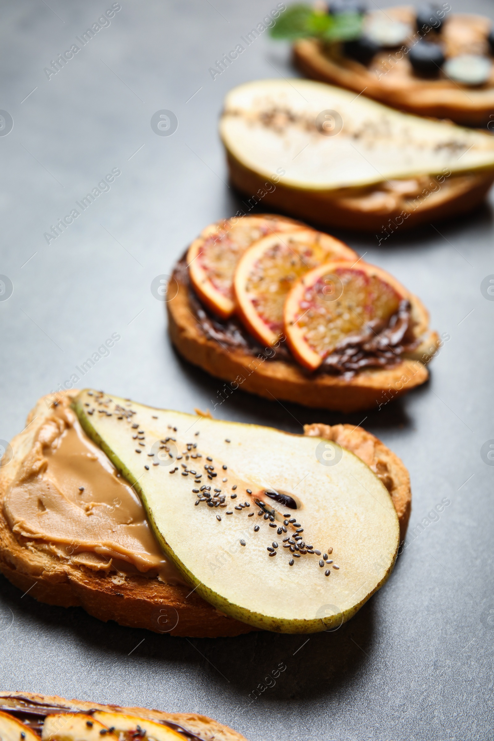 Photo of Tasty toast with pear, peanut butter and chia seeds on grey table