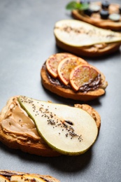 Photo of Tasty toast with pear, peanut butter and chia seeds on grey table
