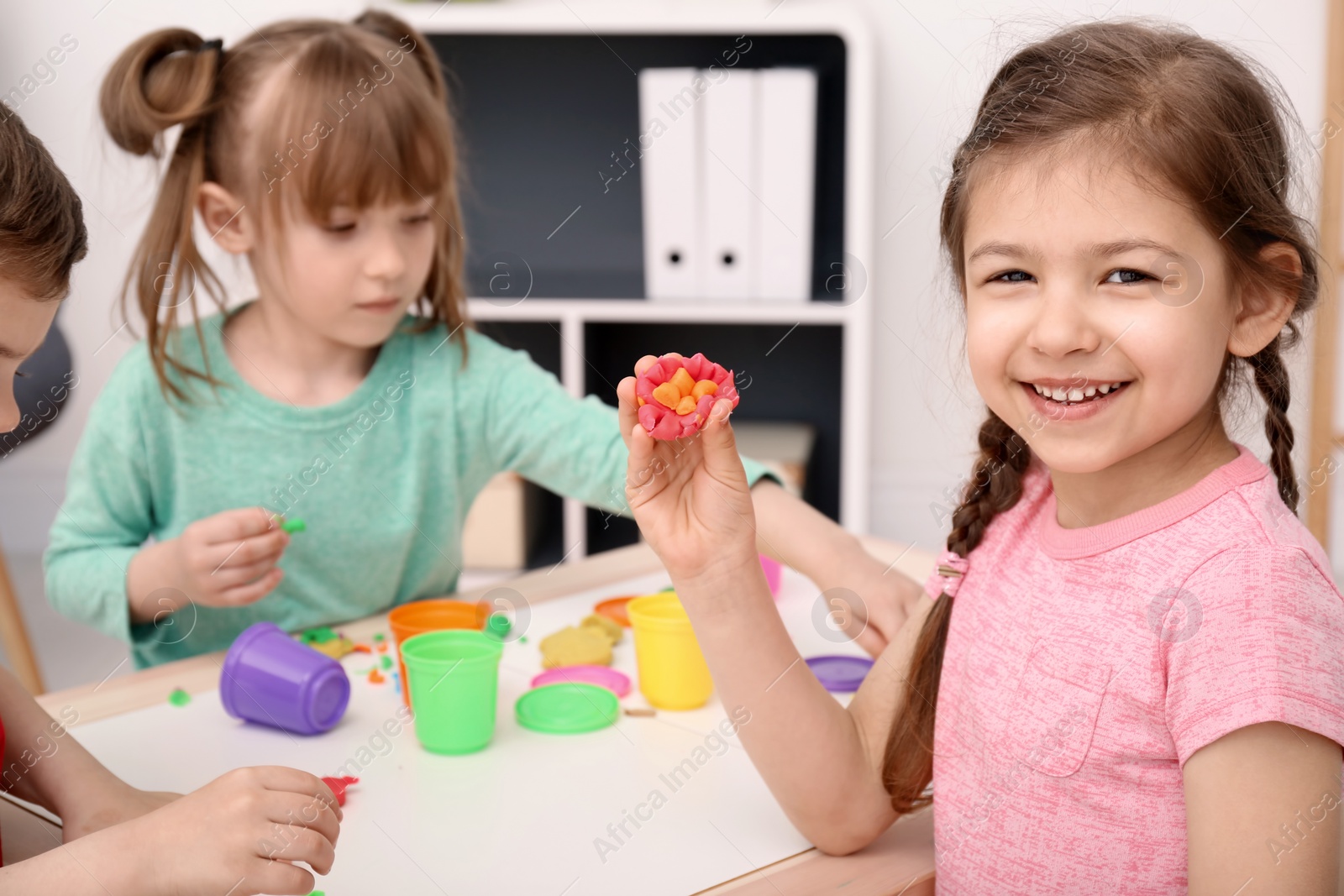 Photo of Cute little children using play dough at table indoors