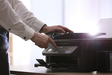 Photo of Employee using modern printer in office, closeup