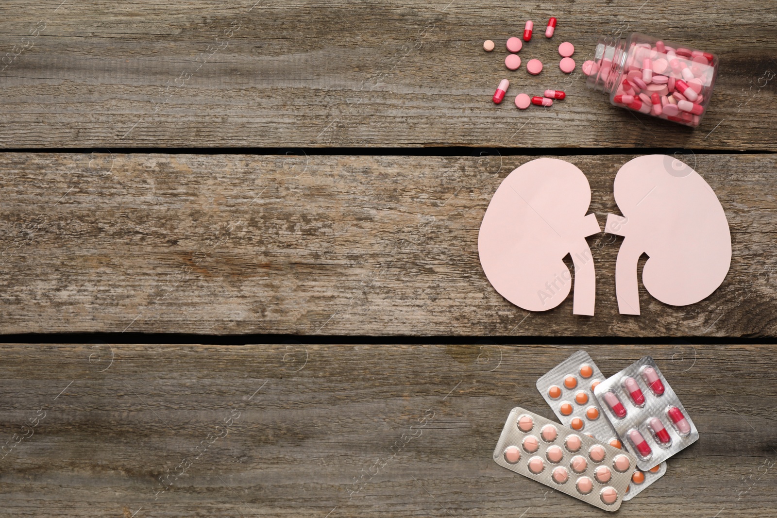 Photo of Paper cutout of kidneys and pills on wooden table, flat lay. Space for text