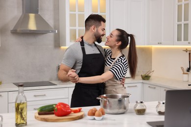 Happy lovely couple dancing together while cooking in kitchen