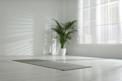 Photo of Unrolled grey yoga mat on floor in room