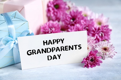 Photo of Beautiful flowers, gift boxes and card with phrase Happy Grandparents Day on grey table