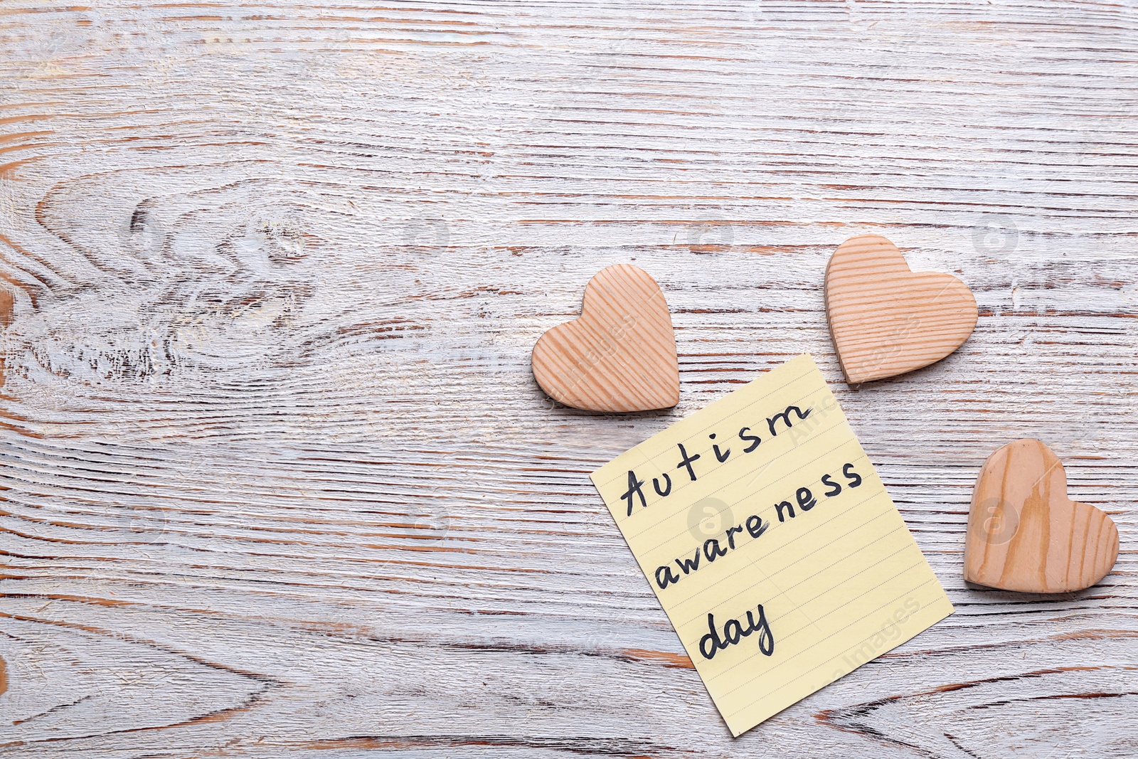 Photo of Sticky note with phrase "Autism awareness day" on wooden background