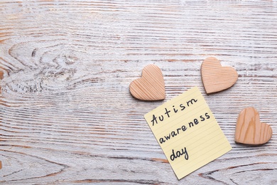 Sticky note with phrase "Autism awareness day" on wooden background