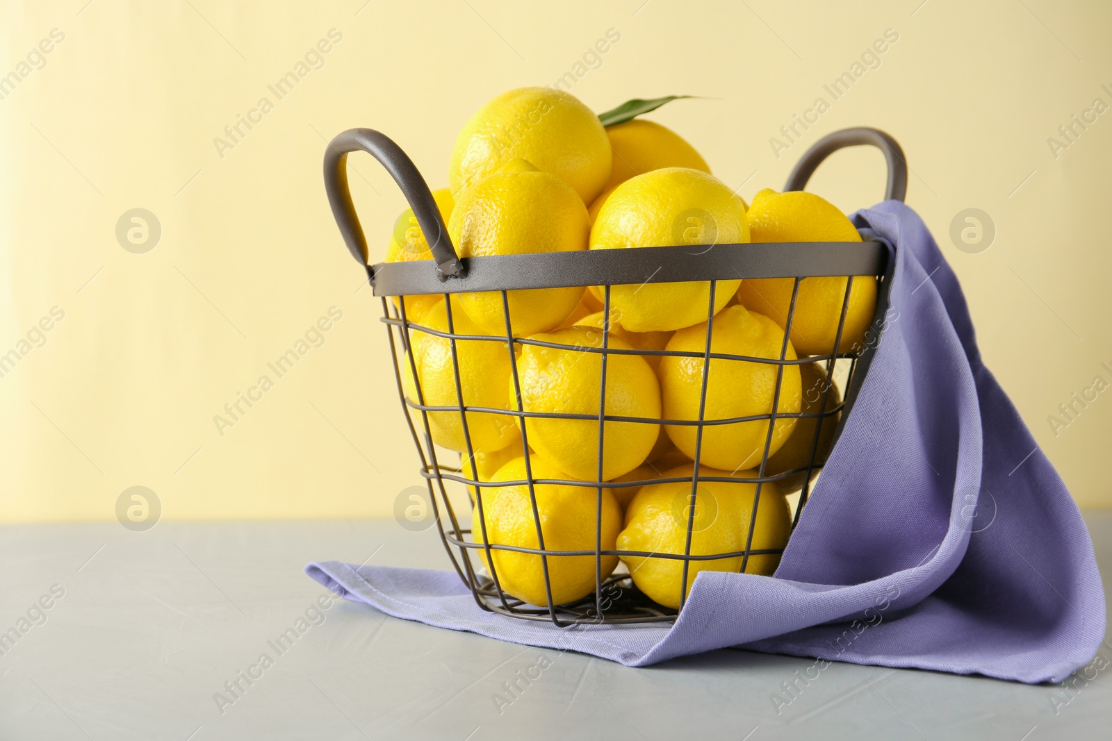 Photo of Metal basket with fresh ripe lemons on table