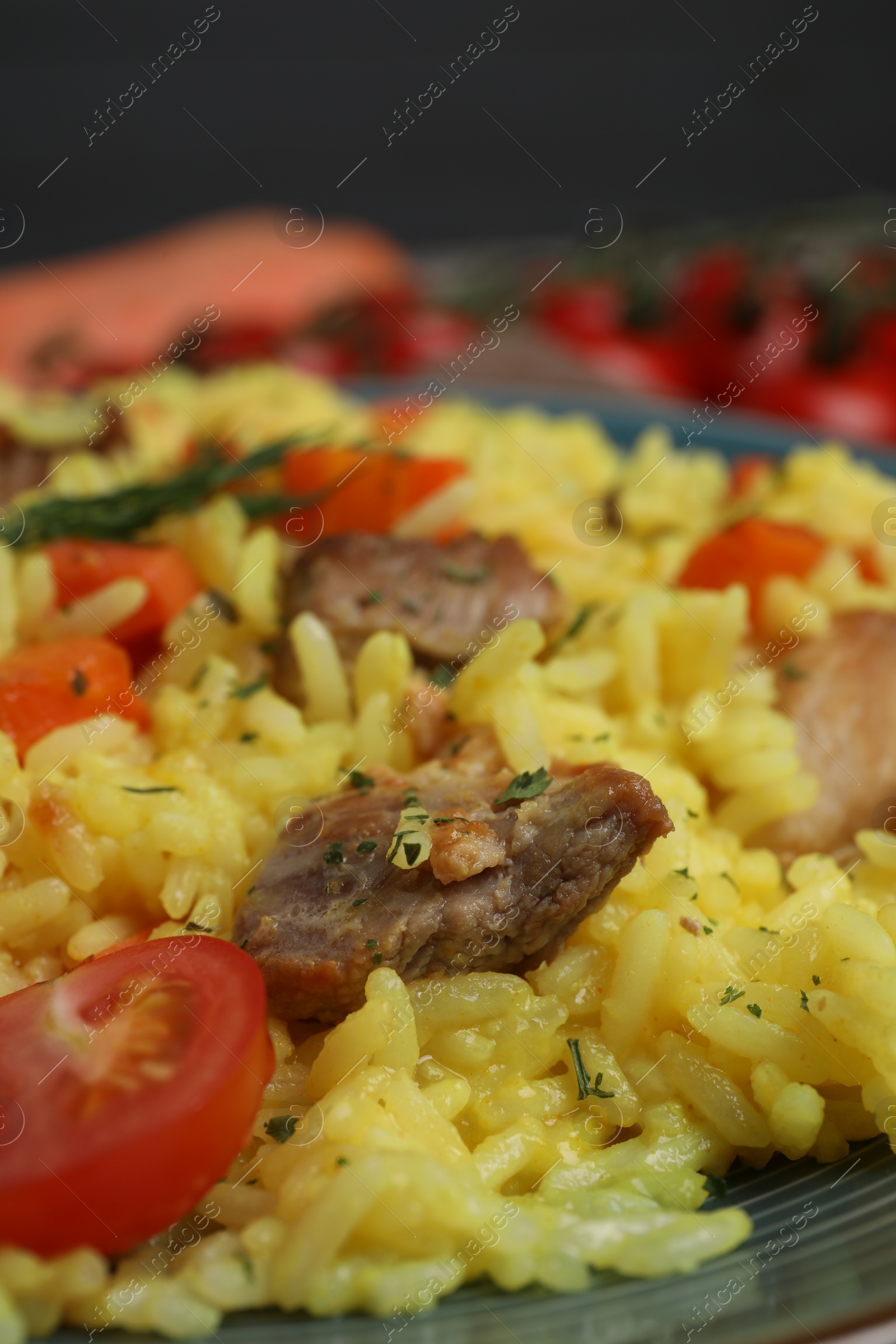 Photo of Delicious pilaf with meat and tomatoes on plate, closeup