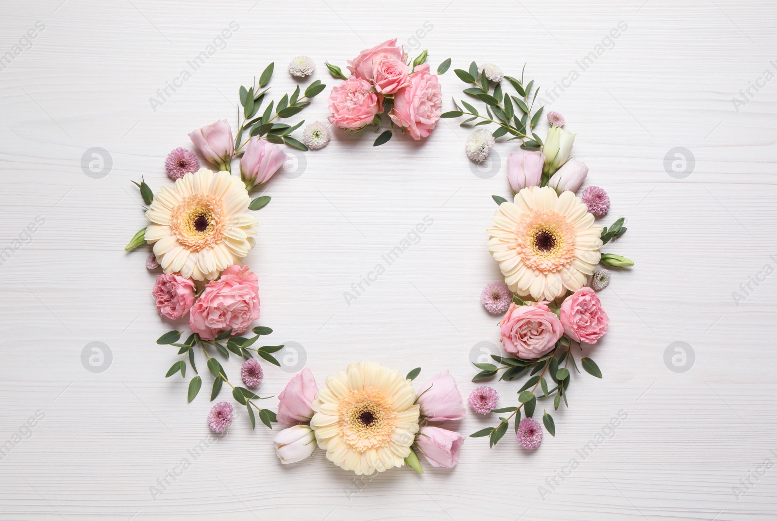 Photo of Wreath made of beautiful flowers and green leaves on white wooden background, flat lay. Space for text