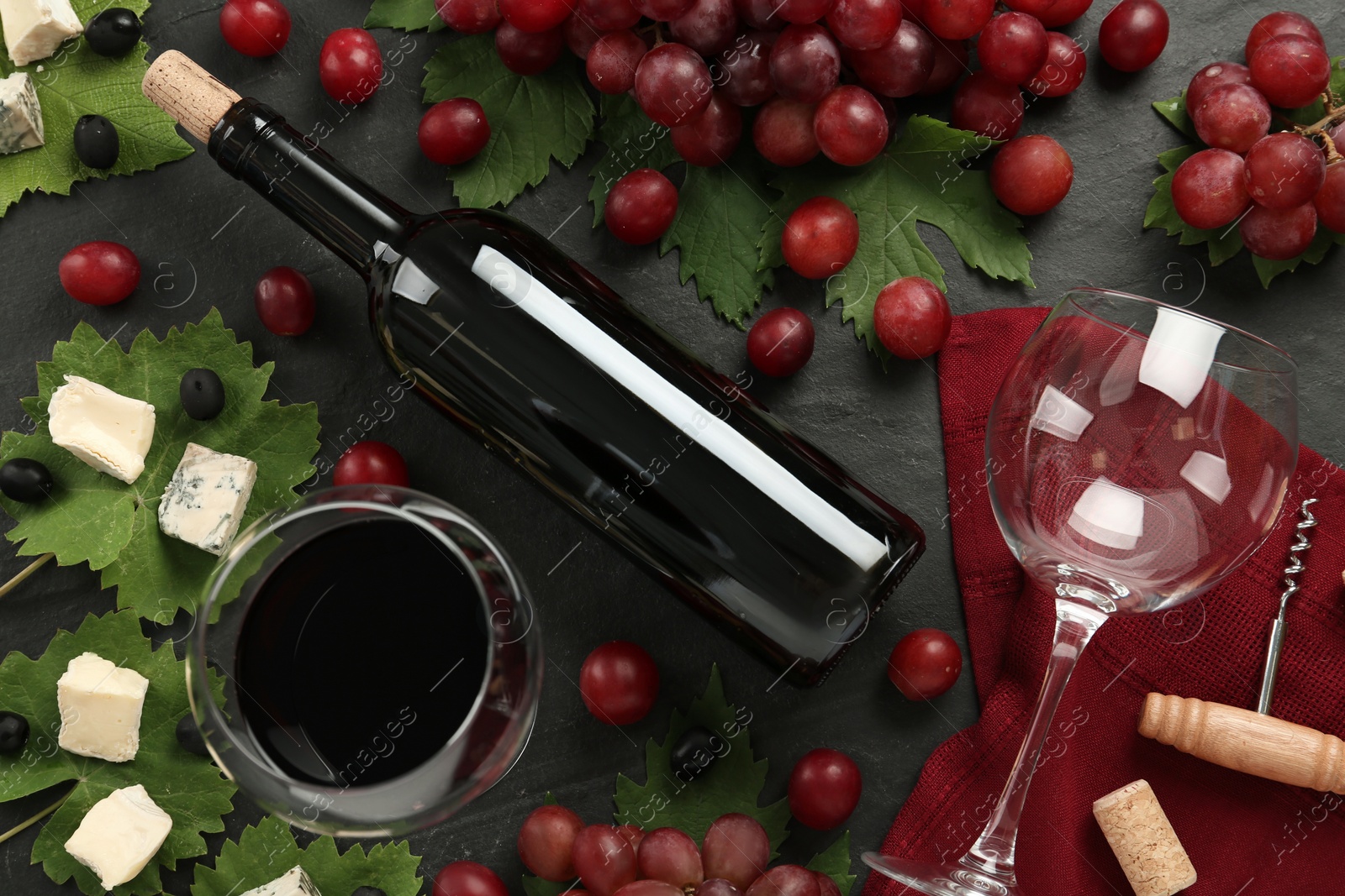 Photo of Tasty red wine and snacks on black table, flat lay