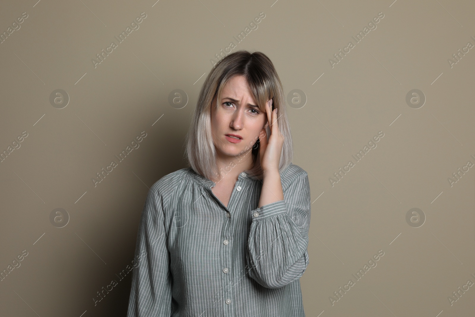 Photo of Woman suffering from headache on beige background