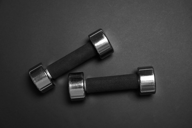 Photo of Metal dumbbells on black background, flat lay