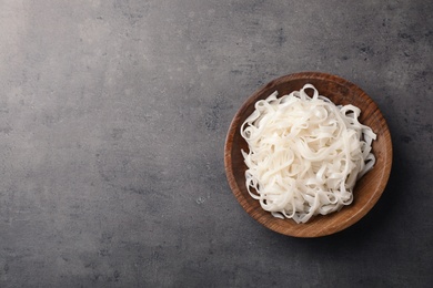 Photo of Bowl with rice noodles on grey background, top view. Space for text