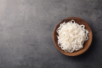 Bowl with rice noodles on grey background, top view. Space for text