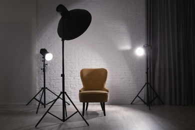 Photo of Interior of modern photo studio with professional lighting equipment and armchair