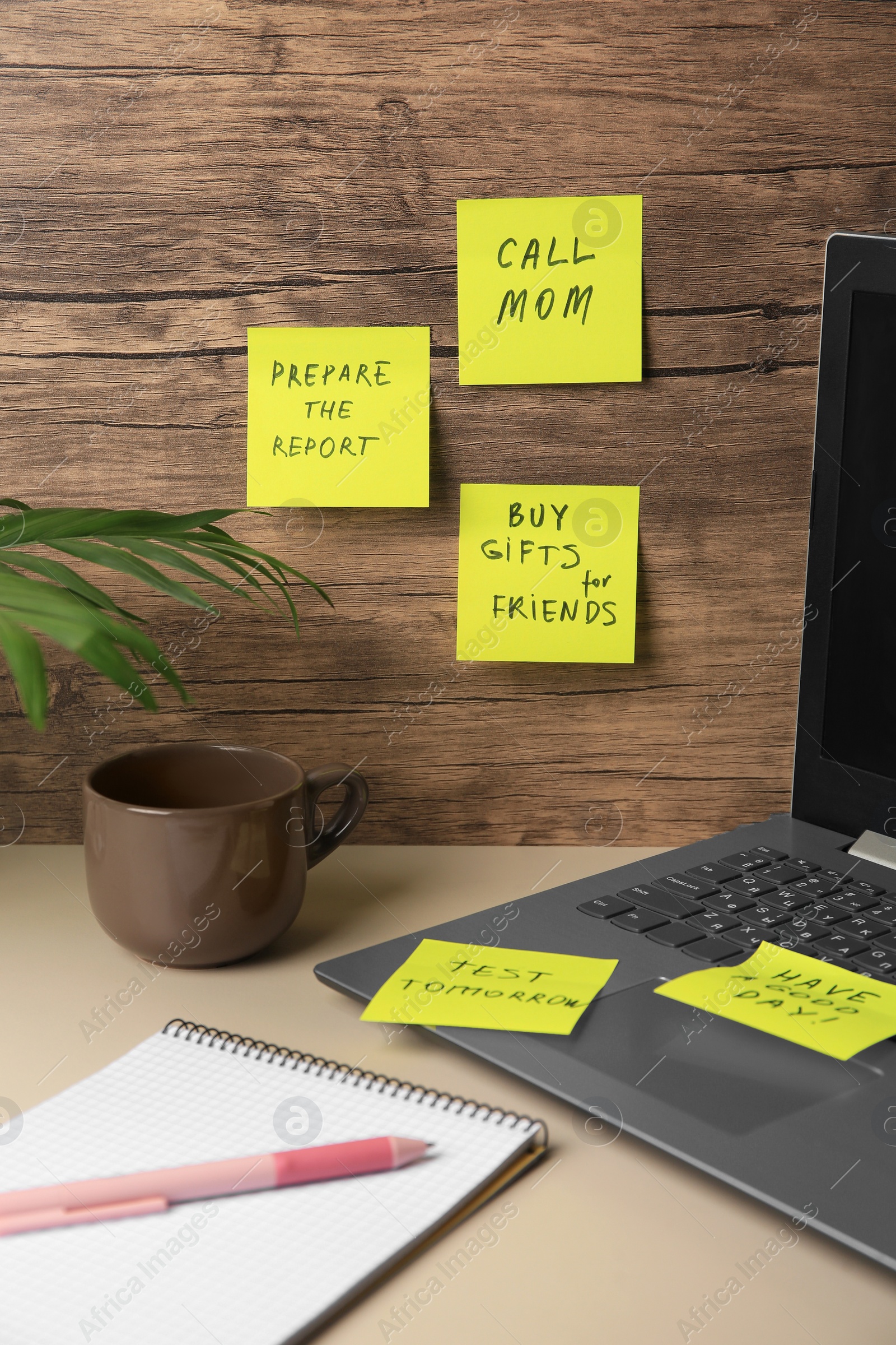 Photo of Many different reminder notes and laptop on white table against wooden background