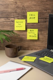 Photo of Many different reminder notes and laptop on white table against wooden background