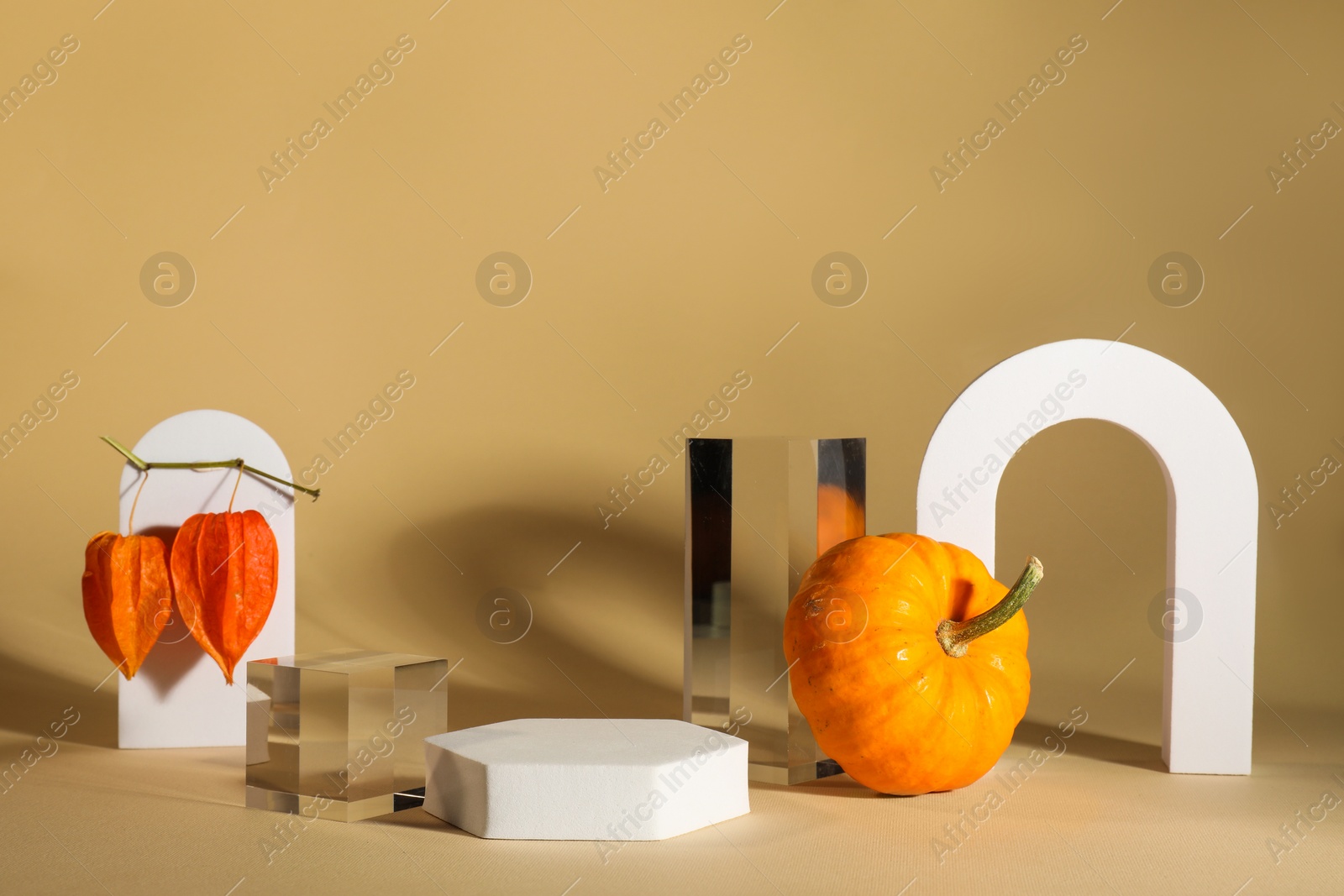 Photo of Stylish presentation for product. Autumn composition with decorative pumpkin and geometric figures on beige background