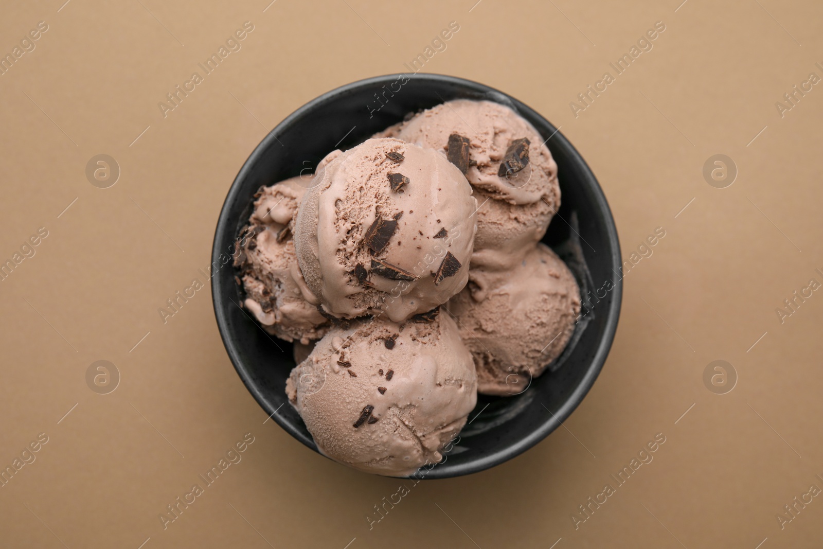 Photo of Bowl with tasty chocolate ice cream on light brown background, top view