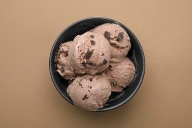 Bowl with tasty chocolate ice cream on light brown background, top view