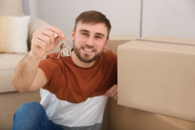 Photo of Happy young man with key from his new house indoors, closeup