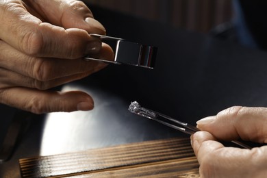 Photo of Professional jeweler working with ring at table, closeup