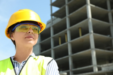 Professional engineer in safety equipment at construction site, space for text
