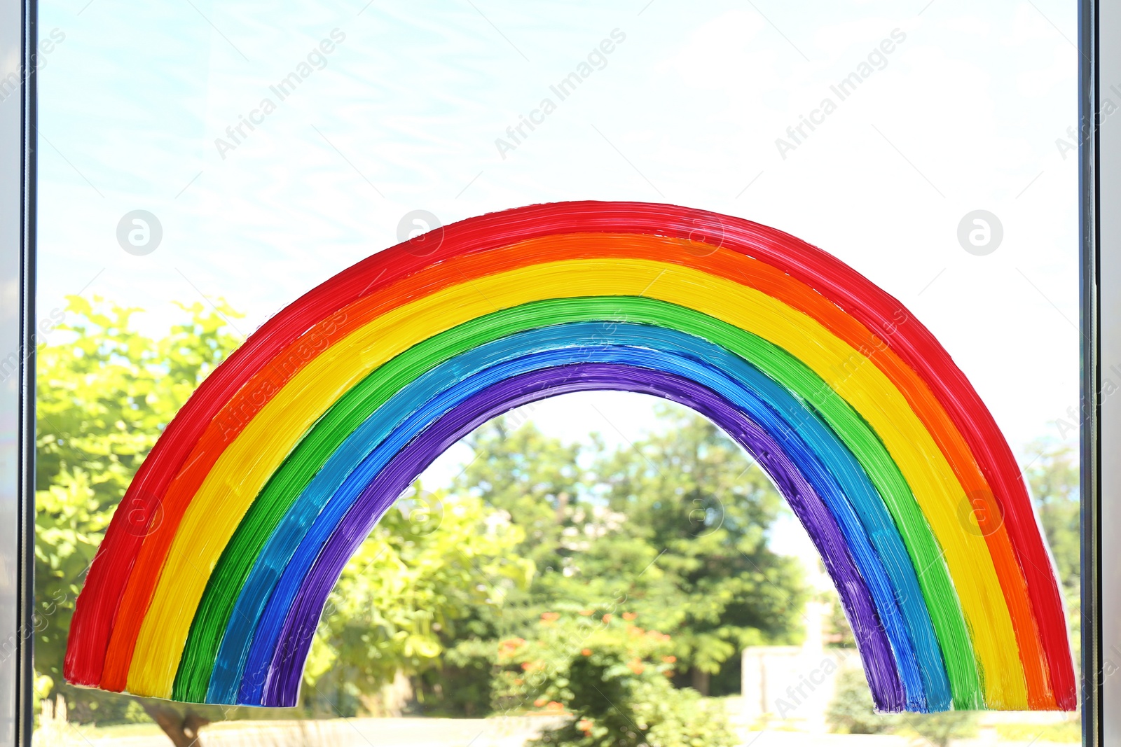 Photo of Painting of rainbow on window. Stay at home concept