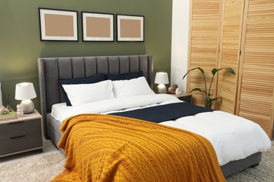 Photo of Large comfortable bed, lamps and houseplant in stylish room. Interior design