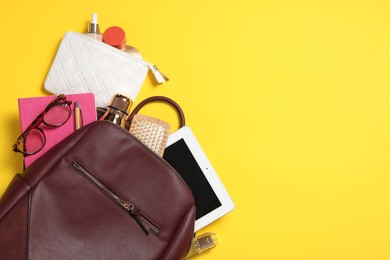 Photo of Stylish urban backpack with different items on yellow background, flat lay. Space for text