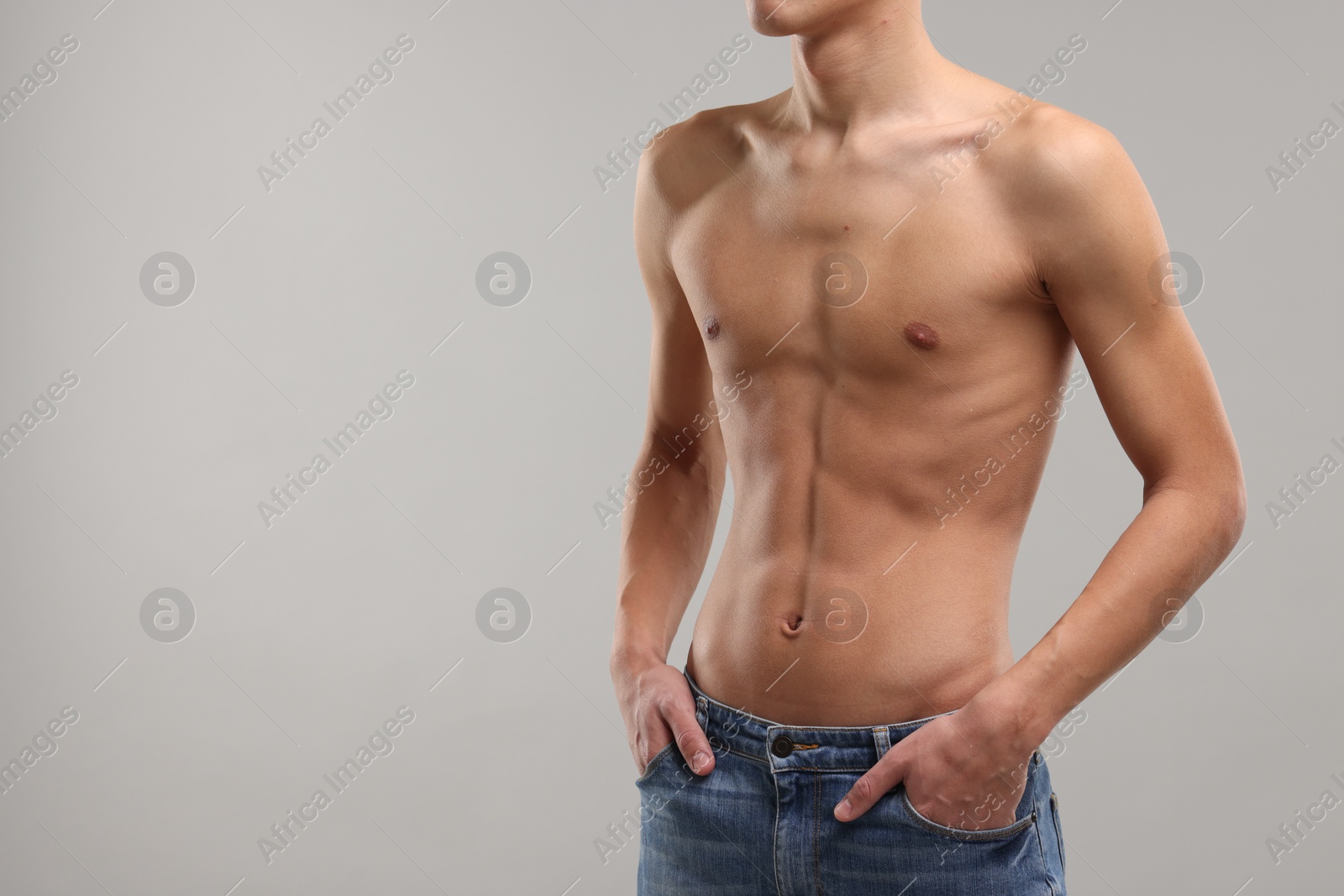 Photo of Shirtless man with slim body on grey background, closeup. Space for text