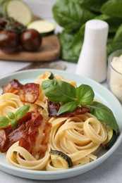 Photo of Tasty pasta with bacon and basil on light grey table