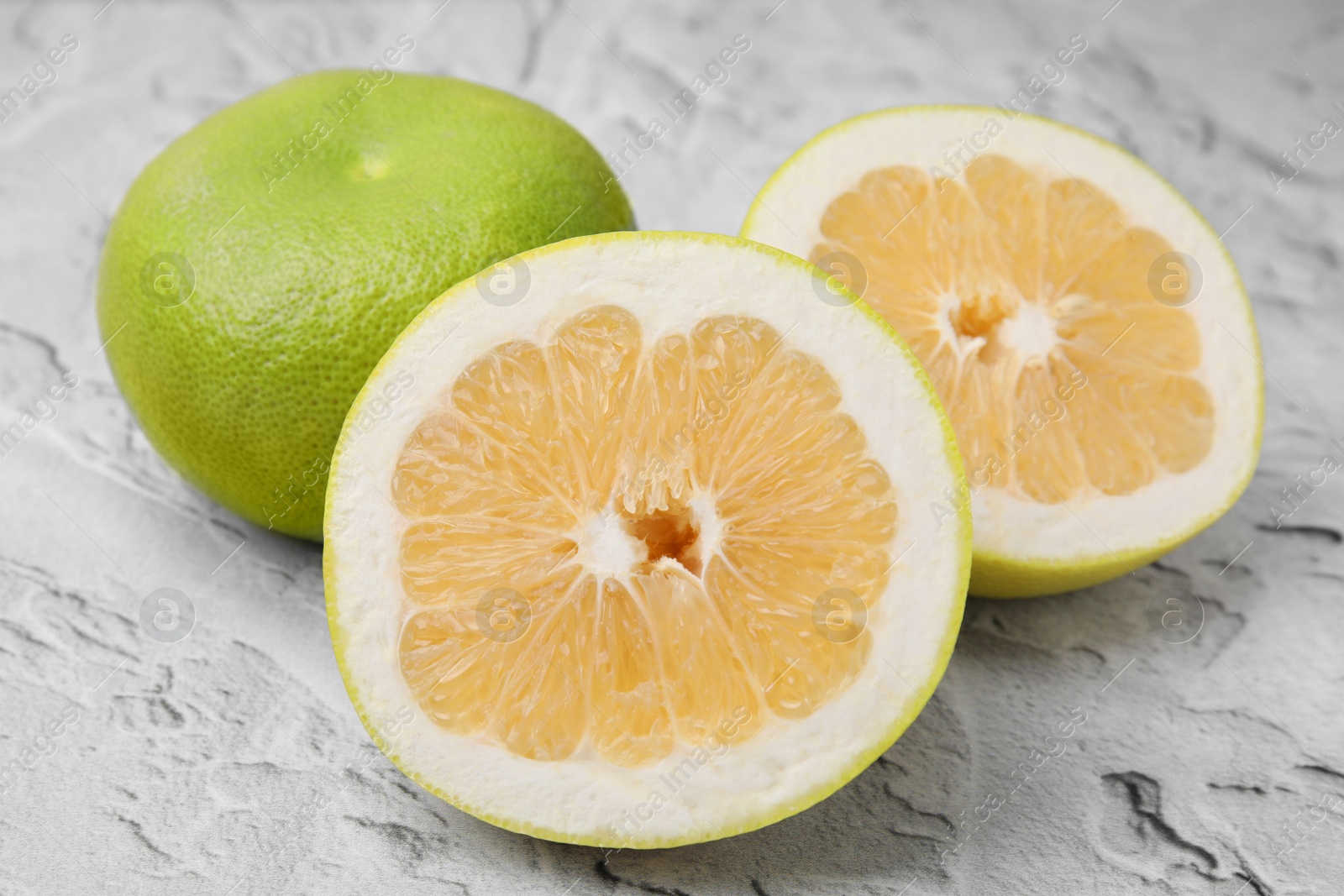 Photo of Whole and cut sweetie fruits on textured table, closeup