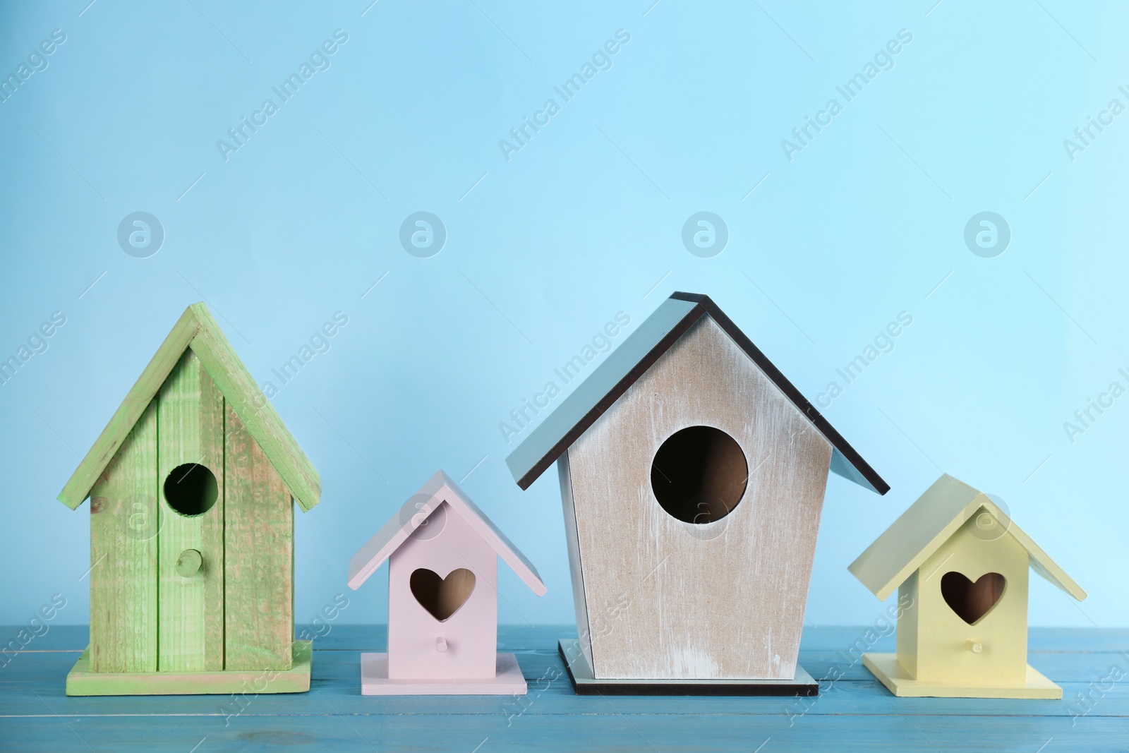 Photo of Collection of handmade bird houses on light blue wooden table