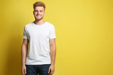 Photo of Young man wearing blank t-shirt on yellow background. Mockup for design