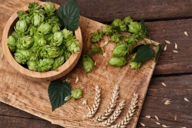 Photo of Fresh green hops and ears of wheat on wooden table, above view