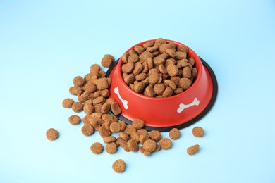 Dry dog food and feeding bowl on light blue background