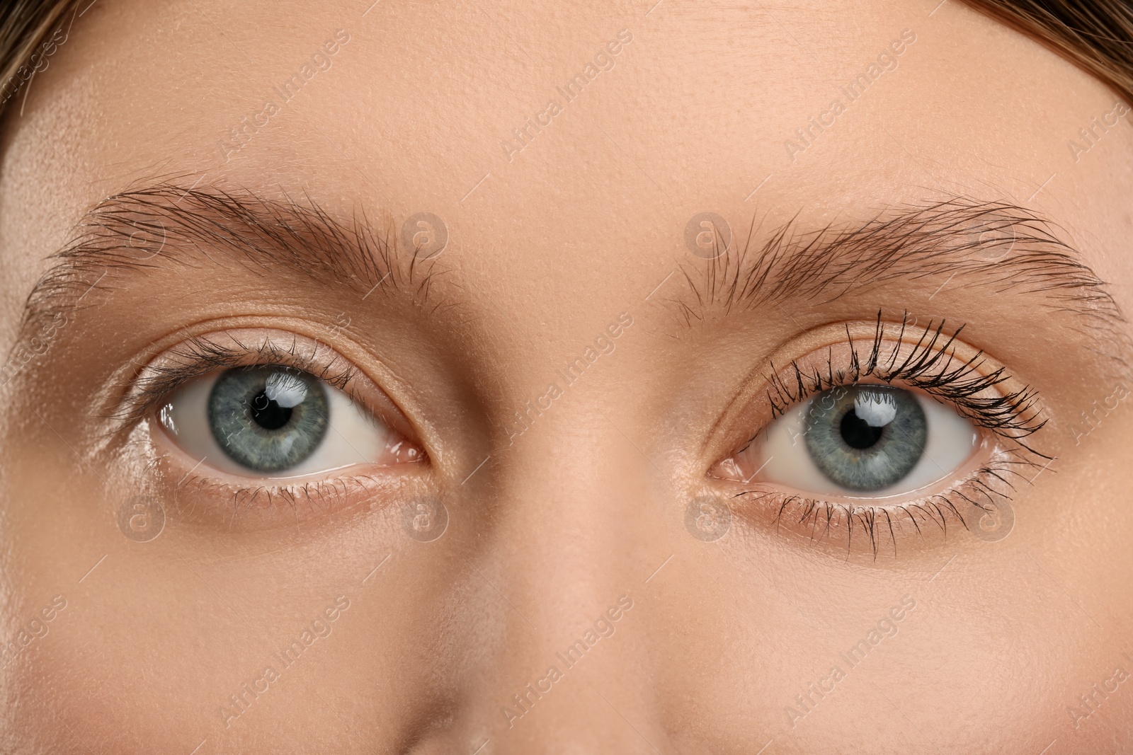 Photo of Woman showing difference in eyelashes length after mascara applying, closeup