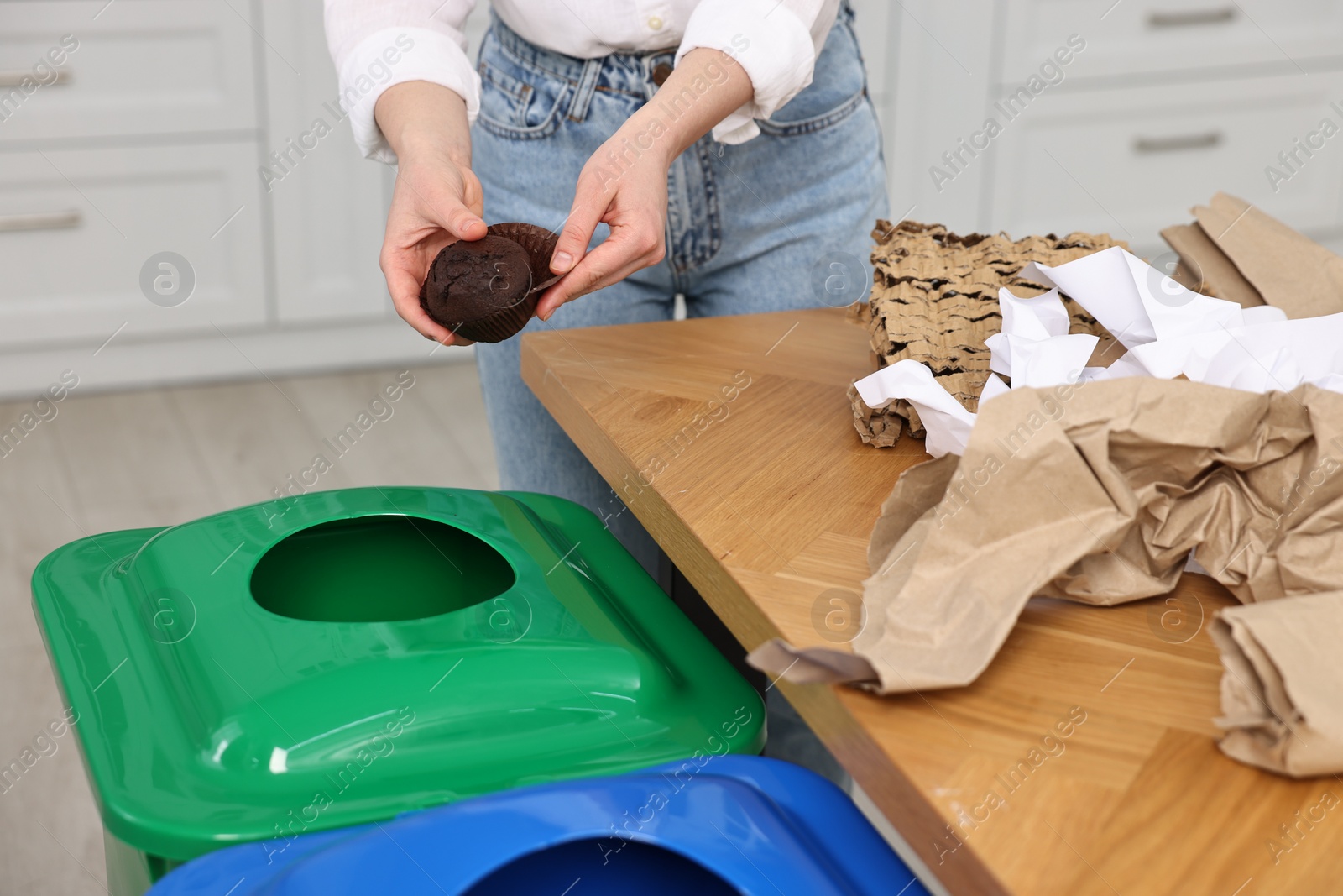 Photo of Garbage sorting. Woman throwing muffin liner into trash bin indoors, closeup