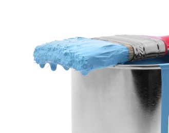 Photo of Can of light blue paint and brush on white background, closeup