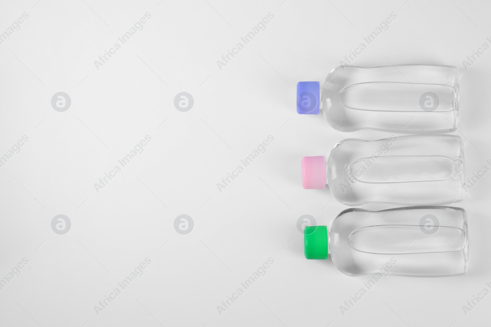 Photo of Transparent bottles with baby oil on white background, flat lay. Space for text