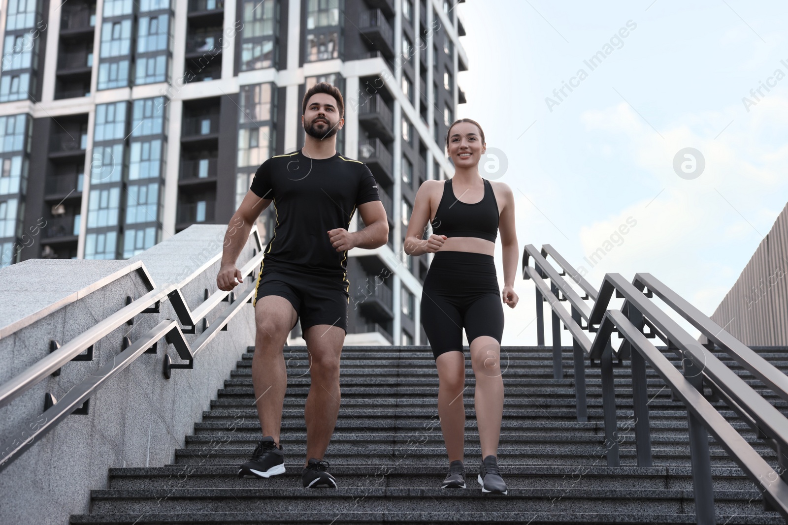 Photo of Healthy lifestyle. Happy couple running on steps outdoors, low angle view