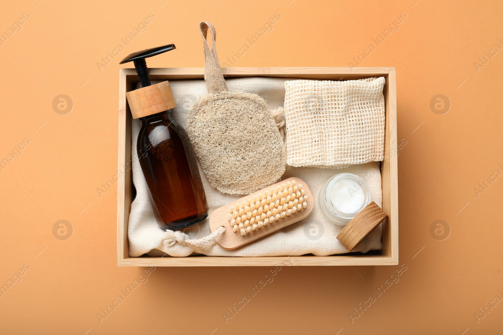 Photo of Eco friendly products in crate on pale orange background, top view