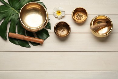 Flat lay composition with golden singing bowls on white wooden table. Space for text